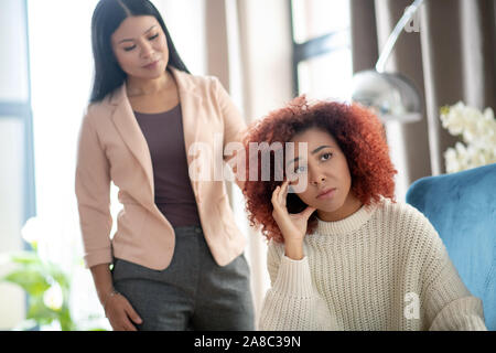 Woman feeling upset but psychoanalyst supporting her Stock Photo
