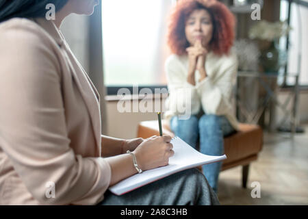 Close up of psychoanalyst wearing bracelet making notes Stock Photo