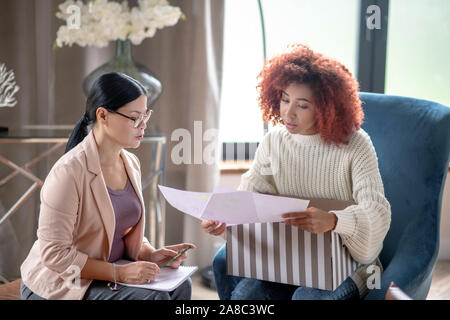 Mature psychoanalyst wearing glasses speaking with client Stock Photo