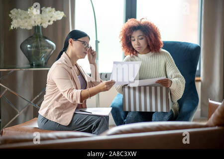 Psychologist wearing glasses helping young unhappy mother Stock Photo