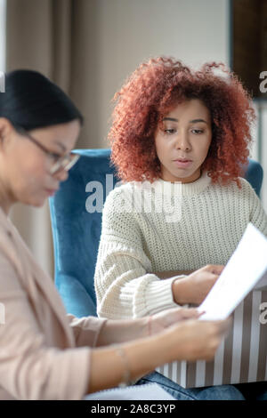 Depressed upset curly young woman having psychoanalysis Stock Photo