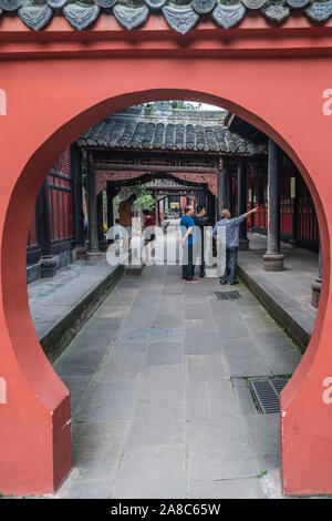 Chengdu, China -  July 2019 : Rounded moongate view of pilgrims or tourists standing in the lengthy corridor in the courtyard of the 17th century Budd Stock Photo