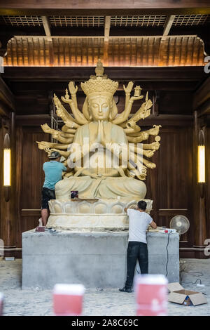 Chengdu, China -  July 2019 :  Male workers creating and restoring large sculpture of multi handed God Shiva in the courtyard of the Buddhist Wenshu M Stock Photo