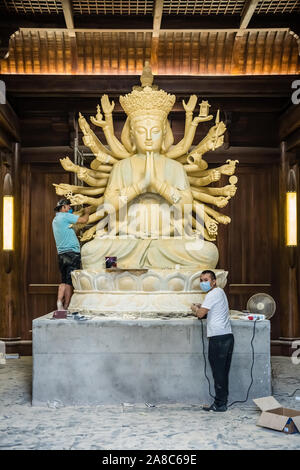 Chengdu, China -  July 2019 :  Male workers creating and restoring large sculpture of multi handed God Shiva in the courtyard of the Buddhist Wenshu M Stock Photo