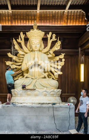 Chengdu, China -  July 2019 :  Male workers creating and restoring large sculpture of multi handed God Shiva in the courtyard of the Buddhist Wenshu M Stock Photo