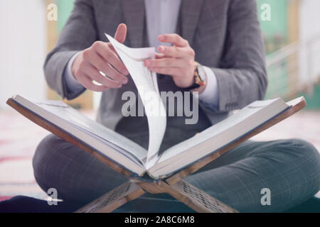 Religious young hafiz muslim man praying inside the mosque and reading holy book of qoran or koran. Stock Photo