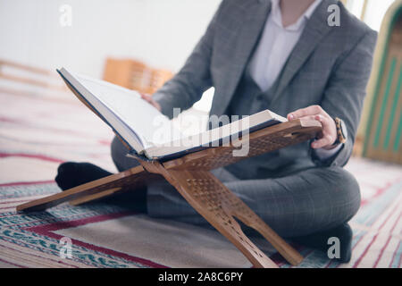 Religious young hafiz muslim man praying inside the mosque and reading holy book of qoran or koran. Stock Photo