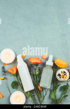 Organic plant based cosmetics concept. Top view of various herbs plants and beauty product containers on vintage blue background. Stock Photo