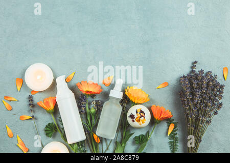 Organic plant based cosmetics concept. Top view of various herbs plants and beauty product containers on vintage blue background. Stock Photo