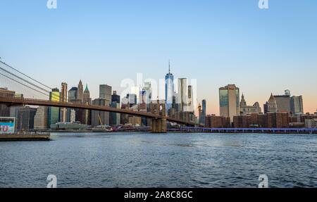 Brooklyn Bridge at sunrise, view from Main Street Park over the East River to the skyline of Manhattan with Freedom Tower or One World Trade Center Stock Photo