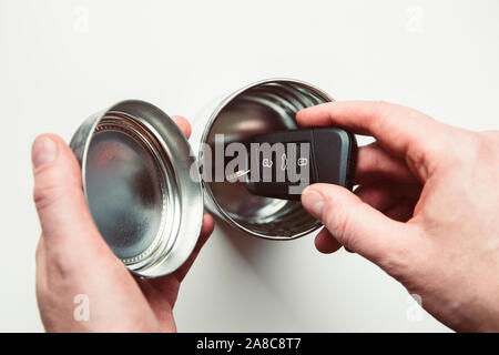 Avoiding high tech start stop system keyless car theft. Man hands put car keys inside metal tin box, removing signal. Stock Photo