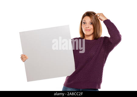 young wondering woman in a purple sweater and jeans, holding a blank board for advertising Stock Photo