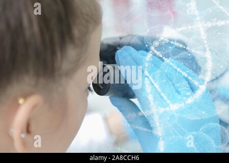 Young female male scientist looking through a microscope in a laboratory doing research, microbiological analysis, medicine. Stock Photo