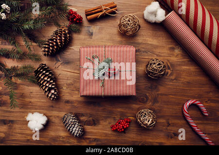 Close-up of gift box decorated for Christmas with beautiful wrapping paper and branch of fir tree on wooden table Stock Photo