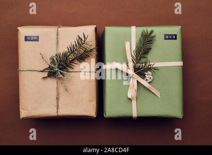 Close-up of two Christmas gift boxes decorated fir branches isolated on brown background Stock Photo