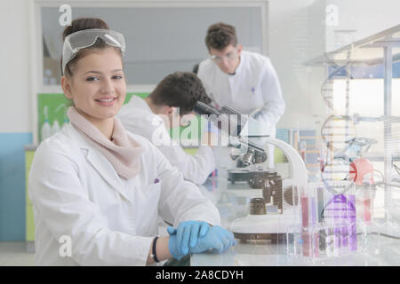 Group of young Laboratory scientists working at lab with test tubes and microscope, test or research in clinical laboratory. Female scientist looking Stock Photo