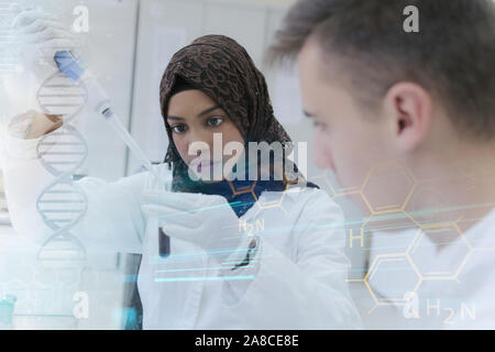 Two young male and female multiethnic, mixed race students  scientists doing experiments in laboratory. Stock Photo