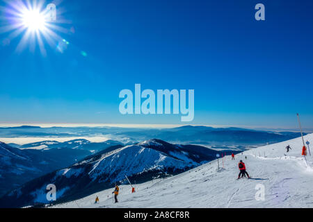 Winter Slovakia. Ski resort Jasna. Panoramic view from the top of the snow-capped mountains and ski slope with skiers Stock Photo