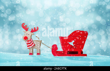 Santa Claus deer and empty sleigh in snow. Cute wooden toy. Copy space above. Stock Photo