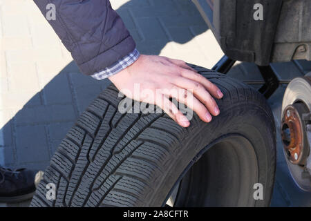 Male hand is changing tyre at car, close up. Wheel balancing or repair and change car tire. Automobile maintenance concept. Stock Photo