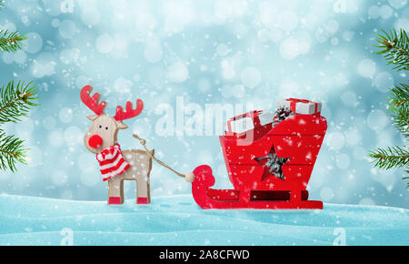 Santa's sleigh full of gifts in snow. Deer pulls the sled. Cute wooden toy. Christmas tree beside. Copy space above. Stock Photo