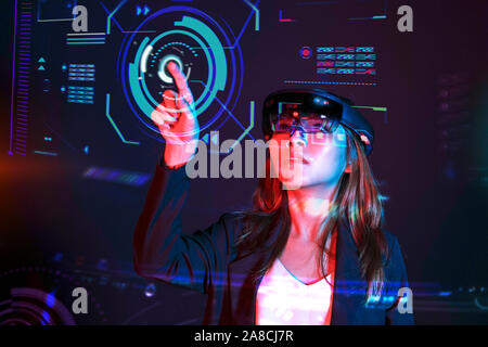 Young asian girl try augmented and virtural reality glasses hololens in the lab room. Mixed reality future technology concept Stock Photo