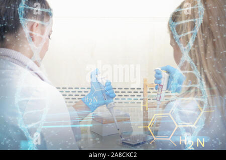 Two young female Laboratory scientists working at lab with test tubes and microscope, test or research in clinical laboratory.Science, chemistry, biol Stock Photo