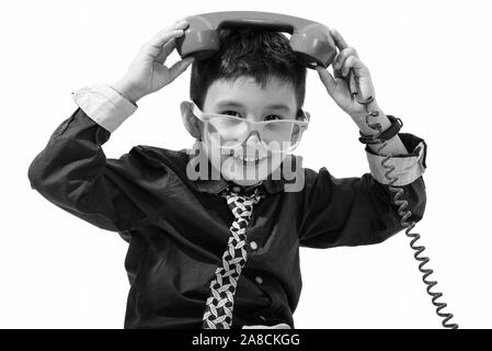 Studio shot of cute happy boy smiling and putting old telephone on head Stock Photo