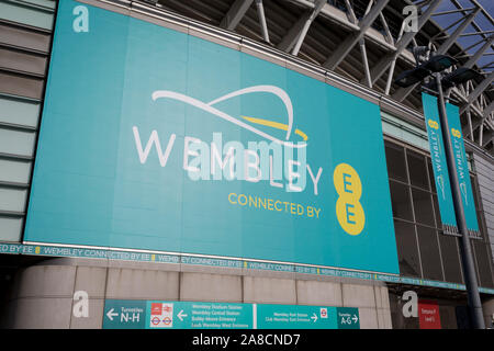 A banner for Wembley Stadium and the communications brand EE, on 6th November 2019, in Wembley, London, England. Wembley Stadium's mobile app and an interactive LED lighting system on the arch, which can respond to goals scored, crowd noise plus trialling contactless payments and ticketing with an aim to make over 50% of payments contactless. In 2018, the world’s first live sporting event to be broadcast over 5G used remote production. Stock Photo