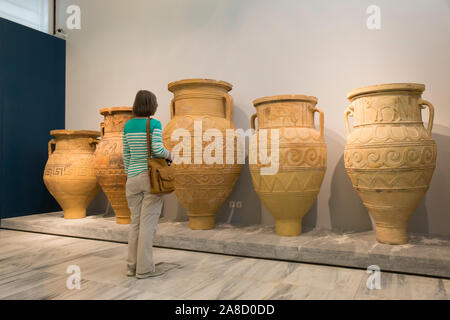 Heraklion, Crete, Greece. Visitor admiring giant earthenware storage jars on display in the Heraklion Archaeological Museum. Stock Photo