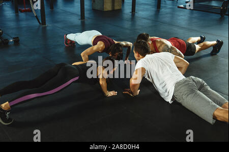 A group of muscular athletes doing workout at the gym. Gymnastics, training, fitness workout flexibility. Active and healthy lifestyle, youth, bodybuilding. Training in stretching and plank. Stock Photo