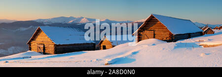 Wooden small houses in mountains. Mountains Carpathians, Ukraine. The picture is made at a dawn in January Stock Photo