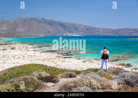 Elafonisi, Chania, Crete, Greece. Visitor on clifftop admiring the view over Vroulia Bay. Stock Photo