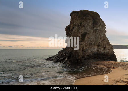 A giant rock at the Carlyon Bay in Cornwall, England. The sun sets beautifully over the sea. Stock Photo