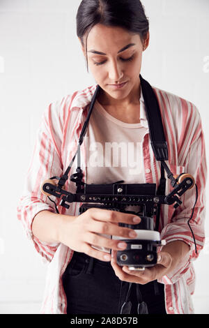 Female Crew Member On Video Film Set Operating Wireless Follow Focus Module In White Studio Stock Photo