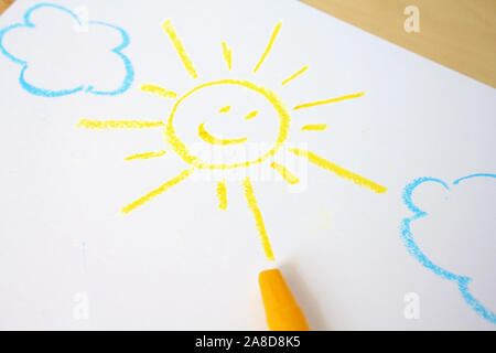 Cute childish drawing by wax crayons. Sun and clouds Stock Photo