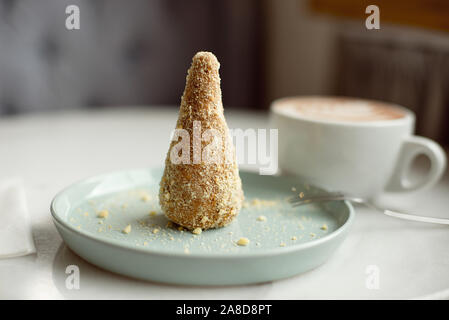 Delicious dessert anthill with dates and crumbs on a mint dessert plate with a cup of cocoa in the background. Stock Photo