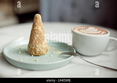 Delicious dessert anthill with dates and crumbs on a mint dessert plate with a cup of cocoa in the background. Stock Photo