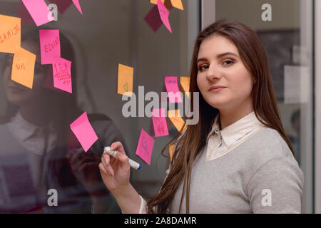 Start up business planning and making organization, young female business woman  at modern office interior writing notes on stickers, prepairing busin Stock Photo