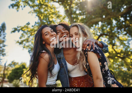 Portrait of a happy multiethnic group of smiling female friends - women laughing and having fun in the park on a sunny day Stock Photo