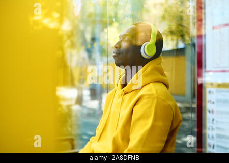 African Young Man Listening To Music At Bus Stop Stock Photo