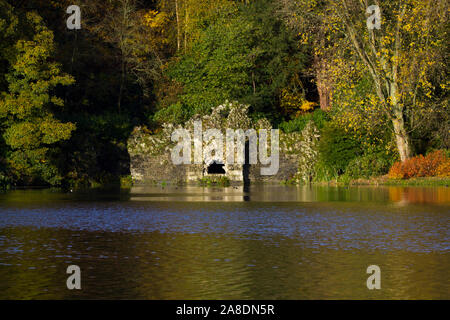 The grotto folly at the Stourhead estate on a sunny autumnal morning. The lake in front and woods behind Stock Photo