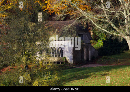 A very sweet little thatched cottage in the woods on the Stourhead estate. A sunny autumnal morning. trees surrounding the house Stock Photo