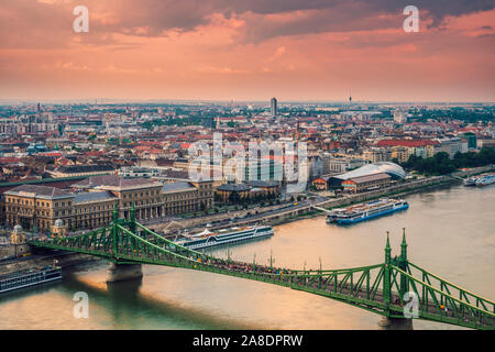 A beautiful panoramic view at sunset of the city of Budapest and the Danube River with the Liberty Bridge in the foreground.View from Gellert Hill. Stock Photo