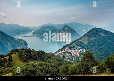 The village of Bre, Lugano Lake , and famous mountains of this area. Beautiful aerial view of a lake, Swiss village and surrounding high mountais. Stock Photo