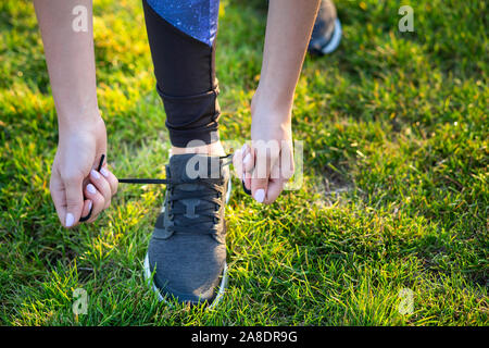 Close-up of female hands tying shoelace on running shoes before practice. Runner getting ready for training. Sport active lifestyle concept. Stock Photo