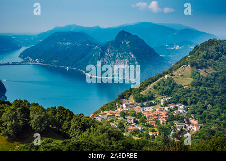 The village of Bre, Lugano Lake , and famous mountains of this area. Beautiful aerial view of a lake, Swiss village and surrounding high mountais. Stock Photo