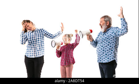 Family members arguing with one another on white studio background. Concept of human emotions, expression, conflict of generations. Woman, man and little girl. Problem of parents and childrens. Stock Photo