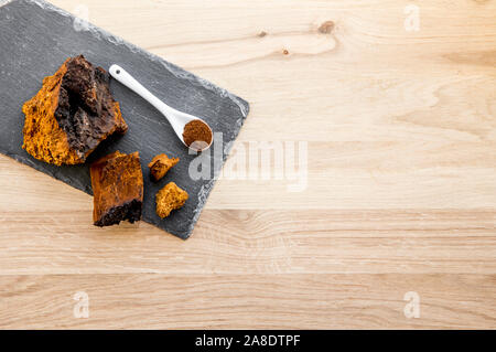 Healthy pure wild natural chaga mushroom, Inonotus obliquus powder and chunks form making tea, coffee and herbal remedy. Gathered from birch tree trun Stock Photo