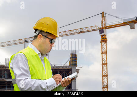 Construction worker man with safety helmet and vest works at construction site. Concept of people working in industrial field Stock Photo